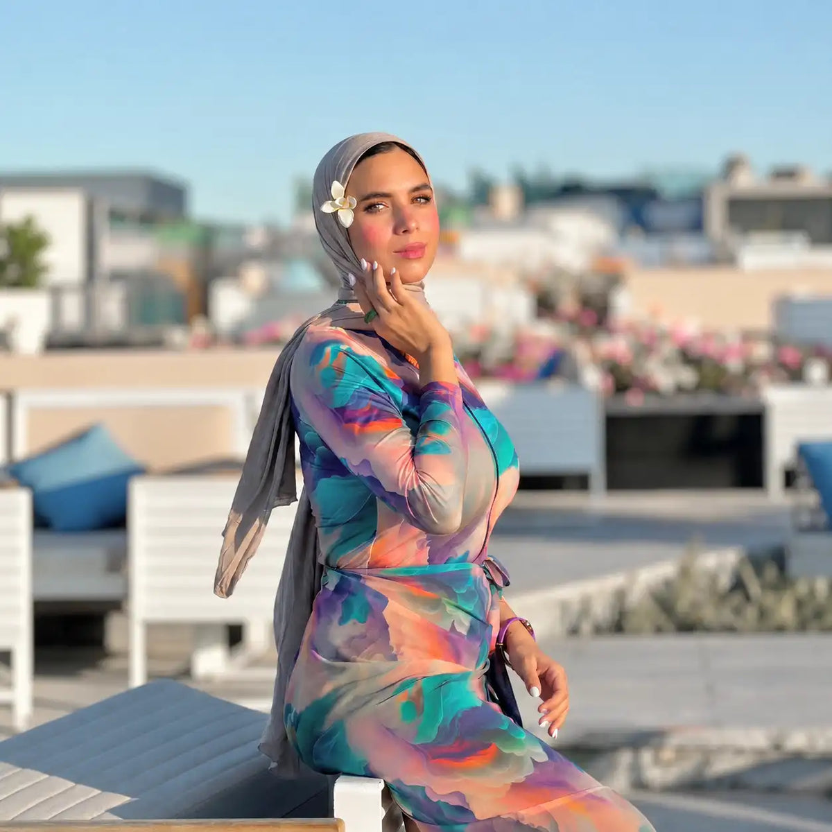 Model in a colourful printed Tallah burkini with a matching headscarf, outdoors by the sea