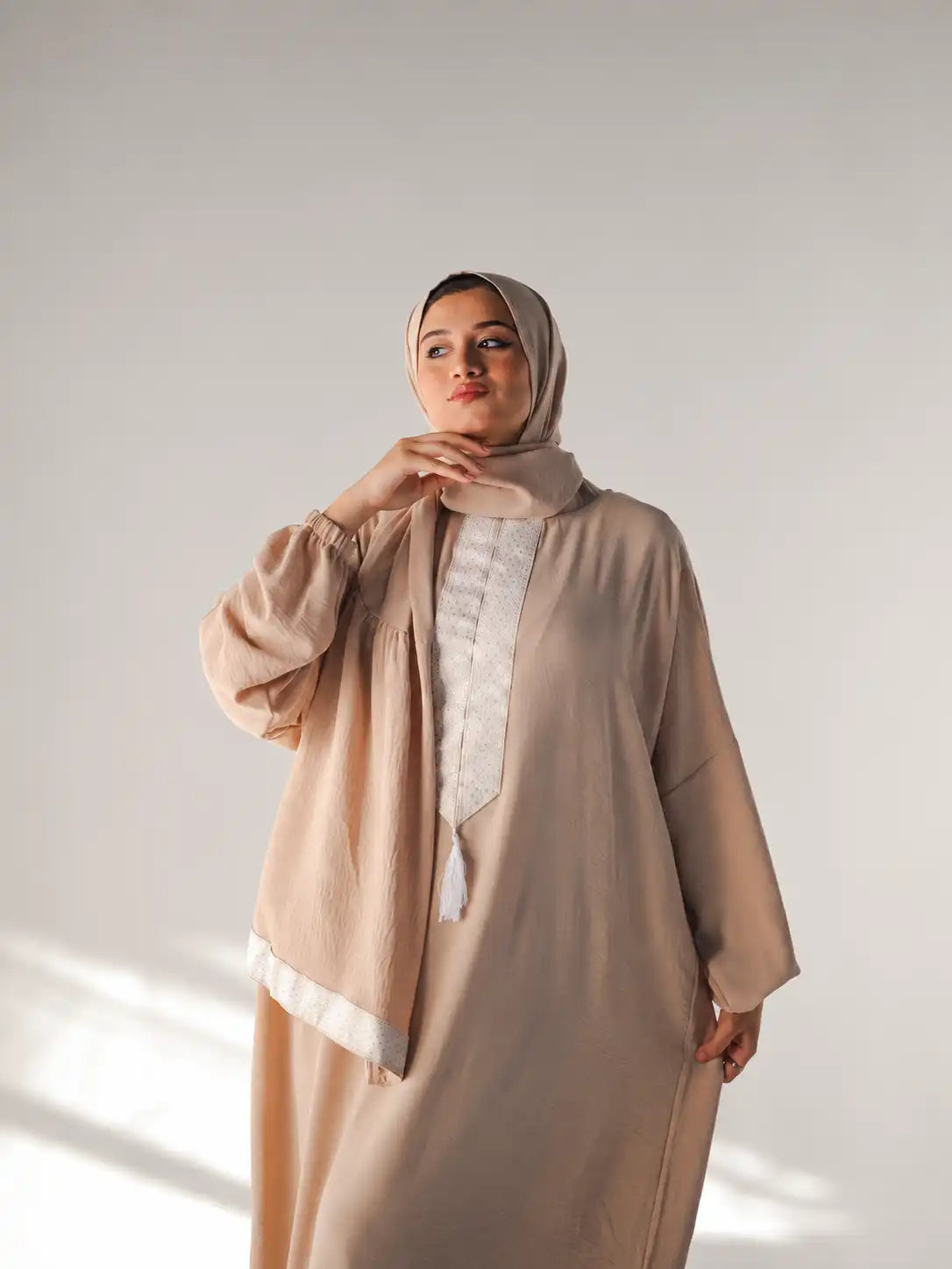 Model in a taupe Tallah Isdal with white woven trim and a matching hijab
