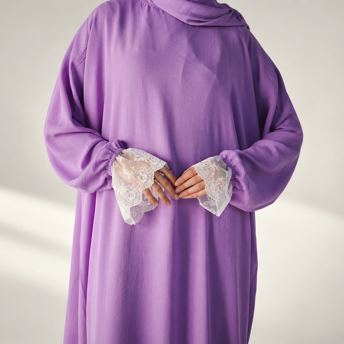 Close-up detail of a cy isdal in lilac, white lace cuffs.