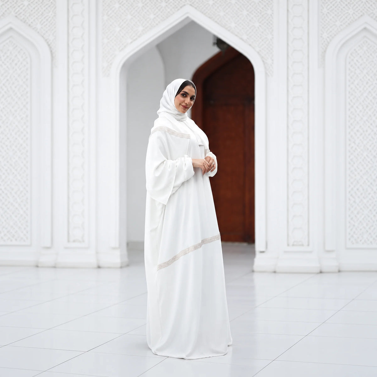 Model wearing Tallah's white CY Isdal with diagonal beaded trim, from the Hajj & Umrah line, gallery photo 1