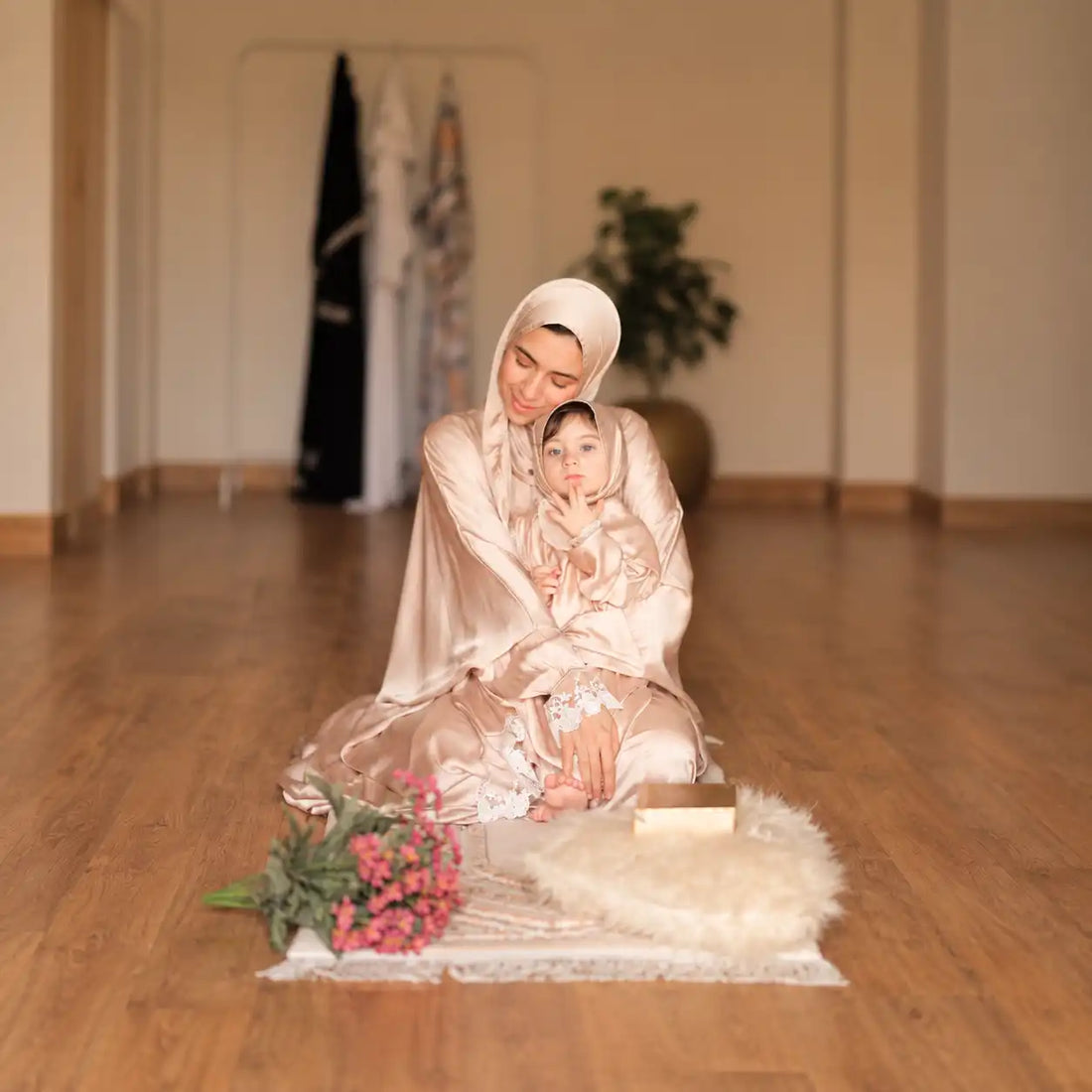 Woman and child in matching light floral Tallah Isdals seated on a cream rug with flowers