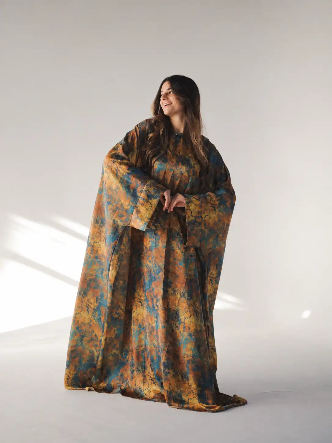 Model in a loose printed Tallah Malhafa with wide sleeves in a studio setting