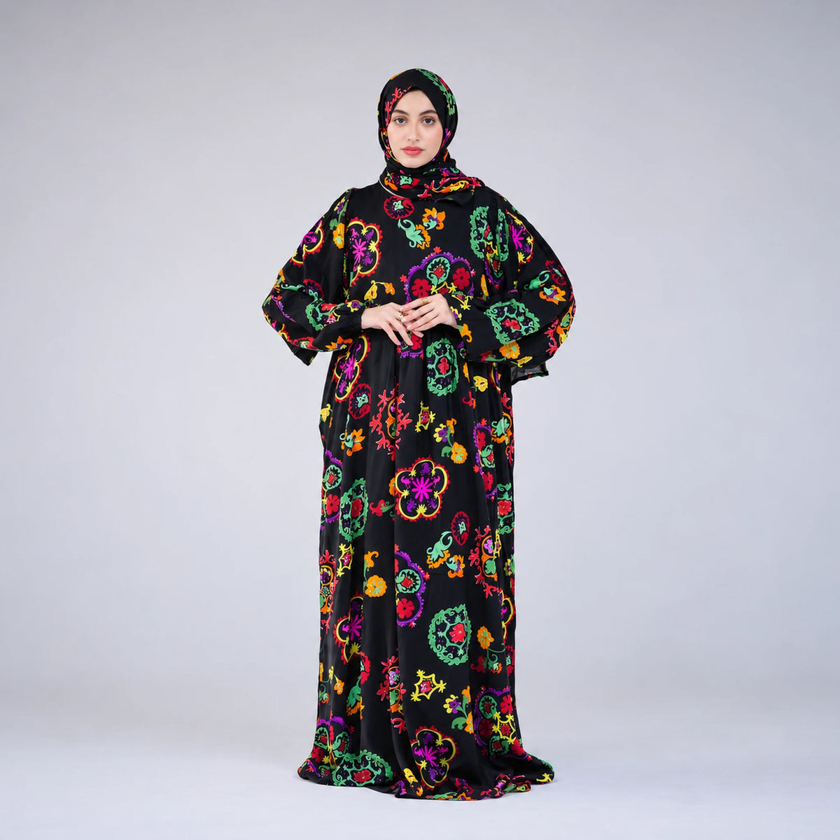 Model wearing Tallah's black Soft Mabrad Isdal with multicolour floral medallions and matching veil, front view with hands together.