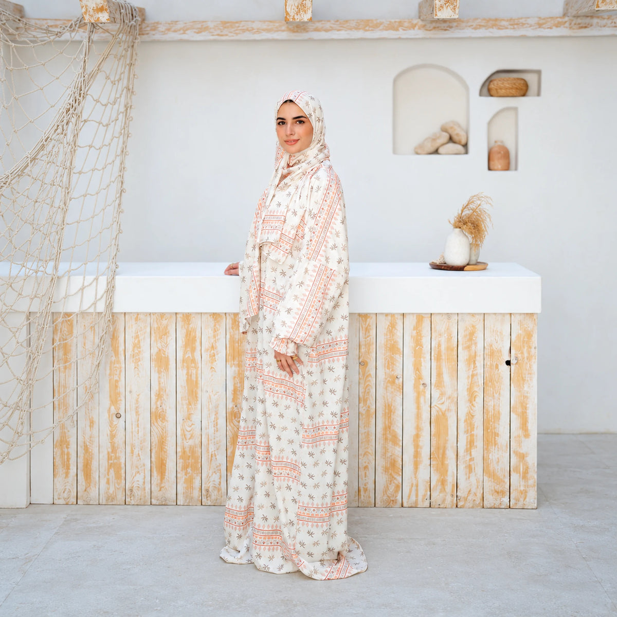 Side view of Tallah's cream Soft Mabrad Isdal with a floral print, peach borders and matching veil.