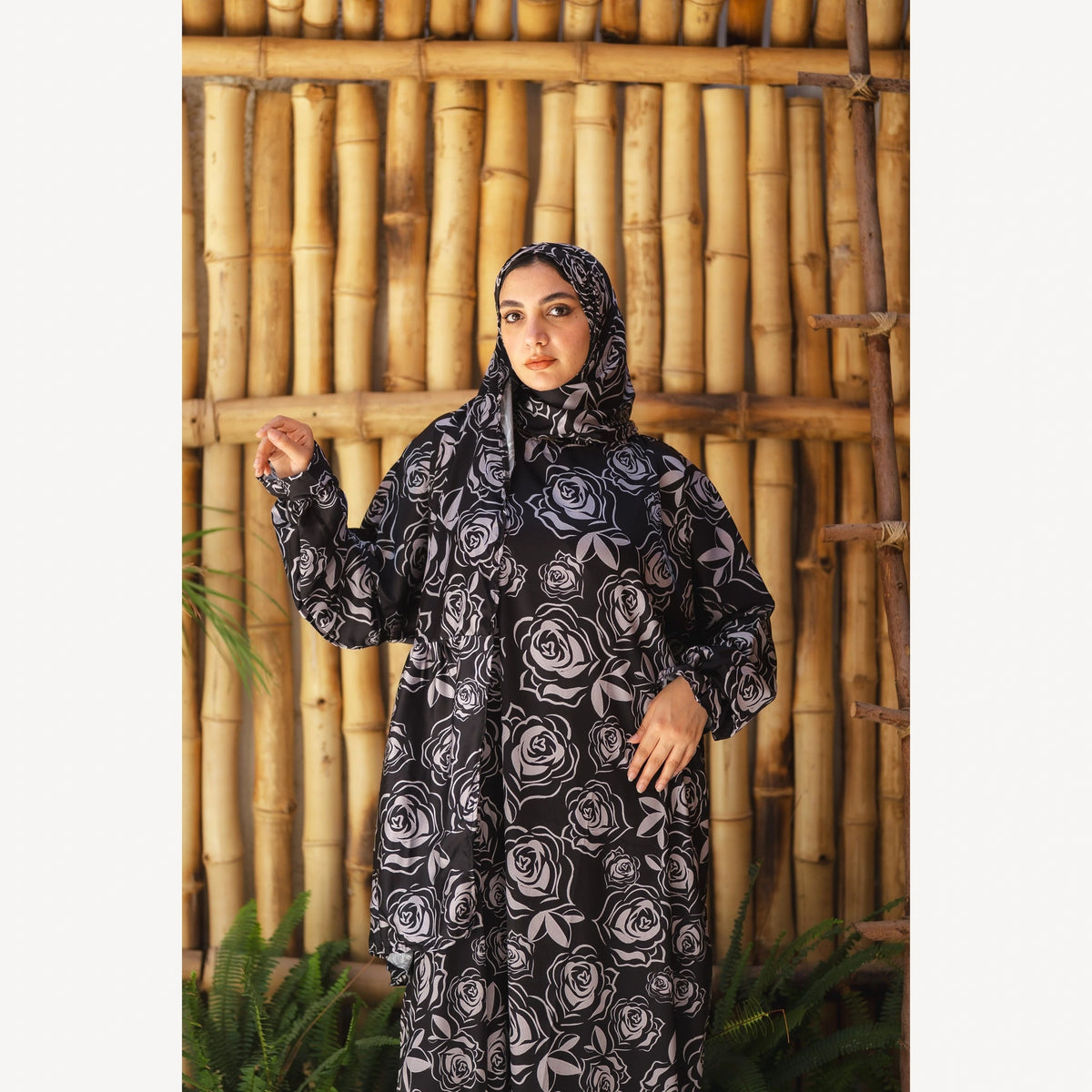 Tallah satin Isdal in black grey rose, closer front view with one hand raised to the side.
