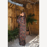 Tallah satin Isdal in black red orange paisley, full-length three-quarter view with one hand near face.