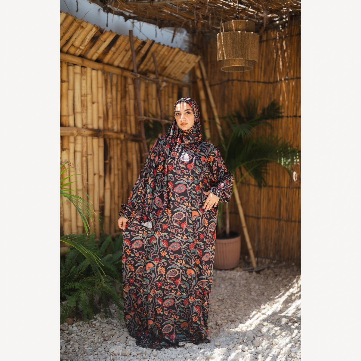 Tallah satin Isdal in black red orange paisley, full-length front view with one hand at hip.