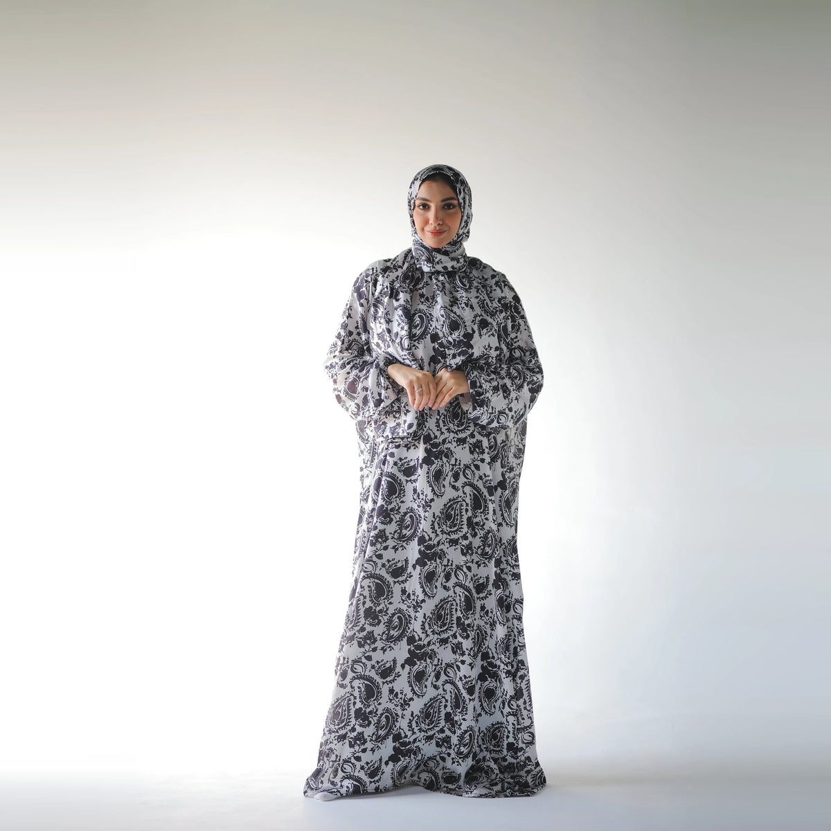 Black and white satin Isdal with paisley and floral motifs, full-length front view with hands together at the waist.