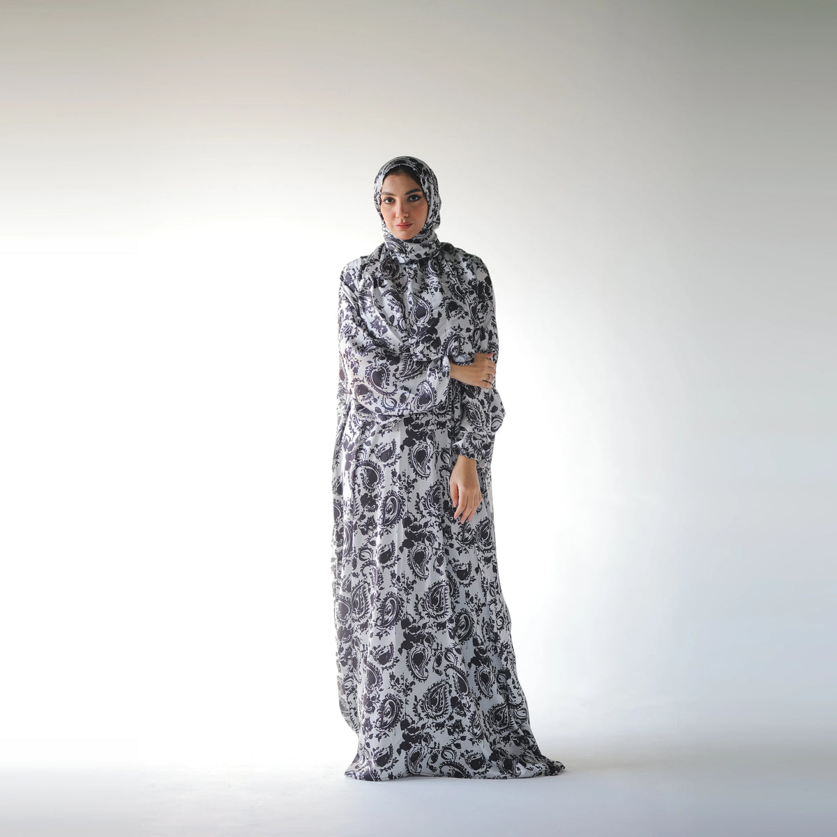Black and white satin Isdal with paisley and floral motifs, full-length front view with one arm across the body.