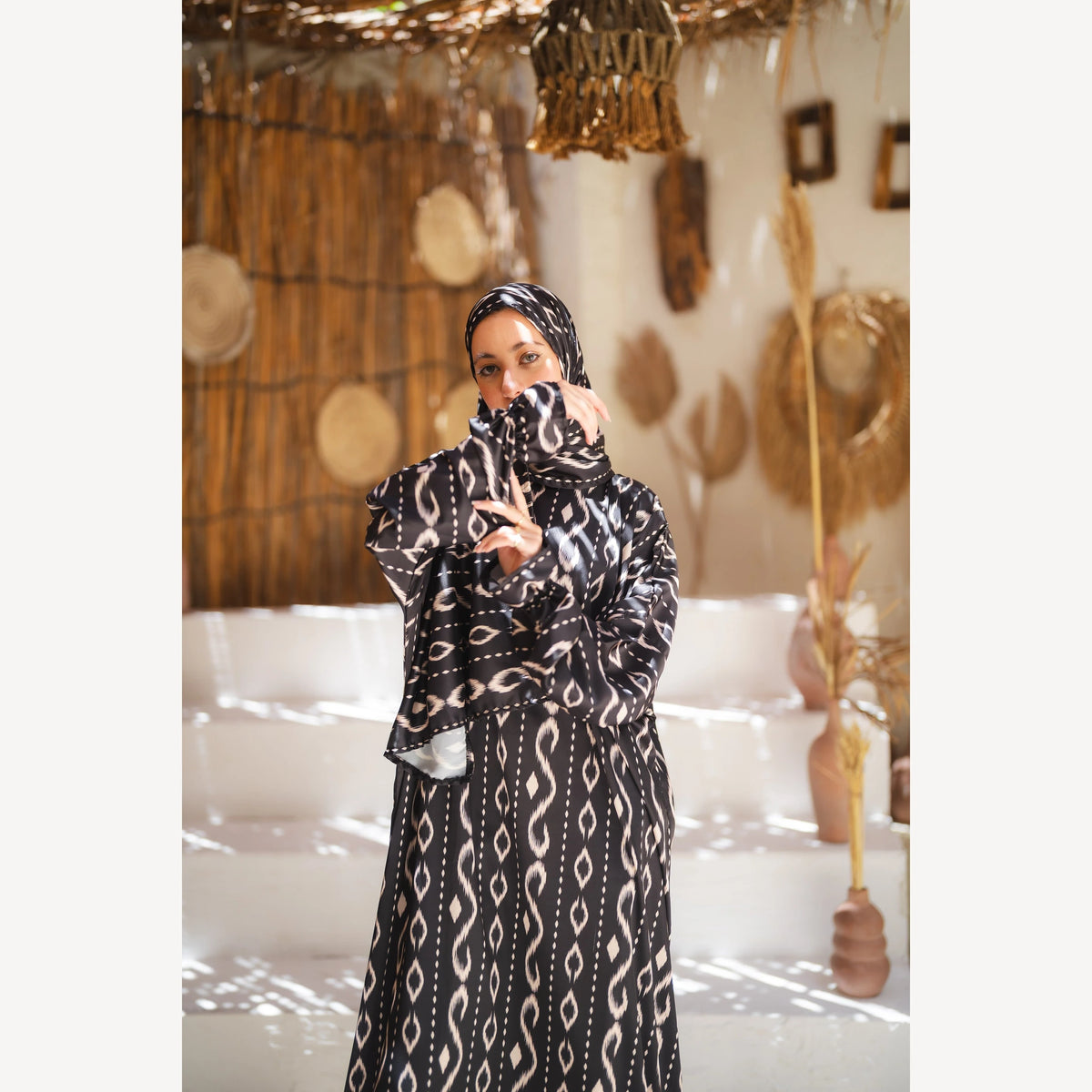 Tallah satin Isdal in black white wave, closer front view with patterned sleeve held near face.