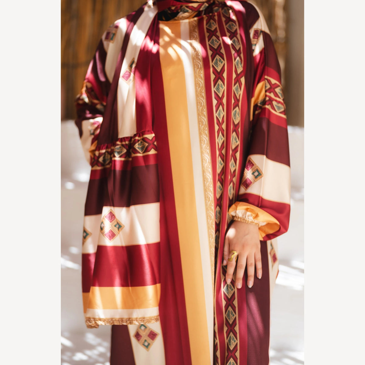 Tallah satin Isdal in burgundy mustard cream striped, close-up of patterned satin bodice, sleeve and hand.