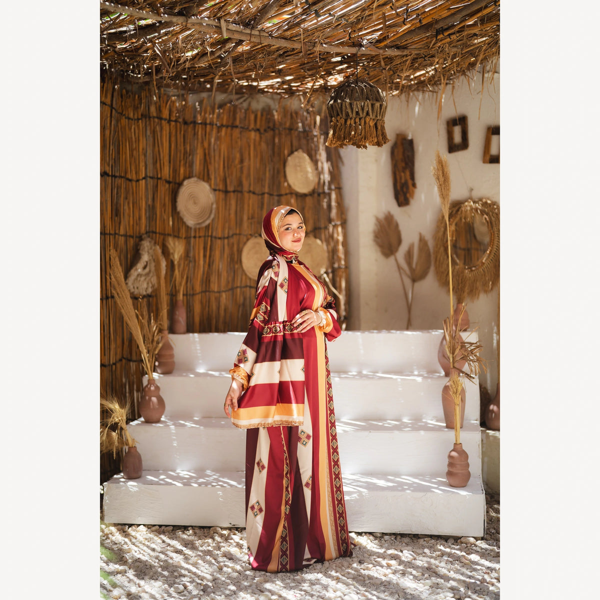 Tallah satin Isdal in burgundy mustard cream striped, full-length three-quarter view with hands together.
