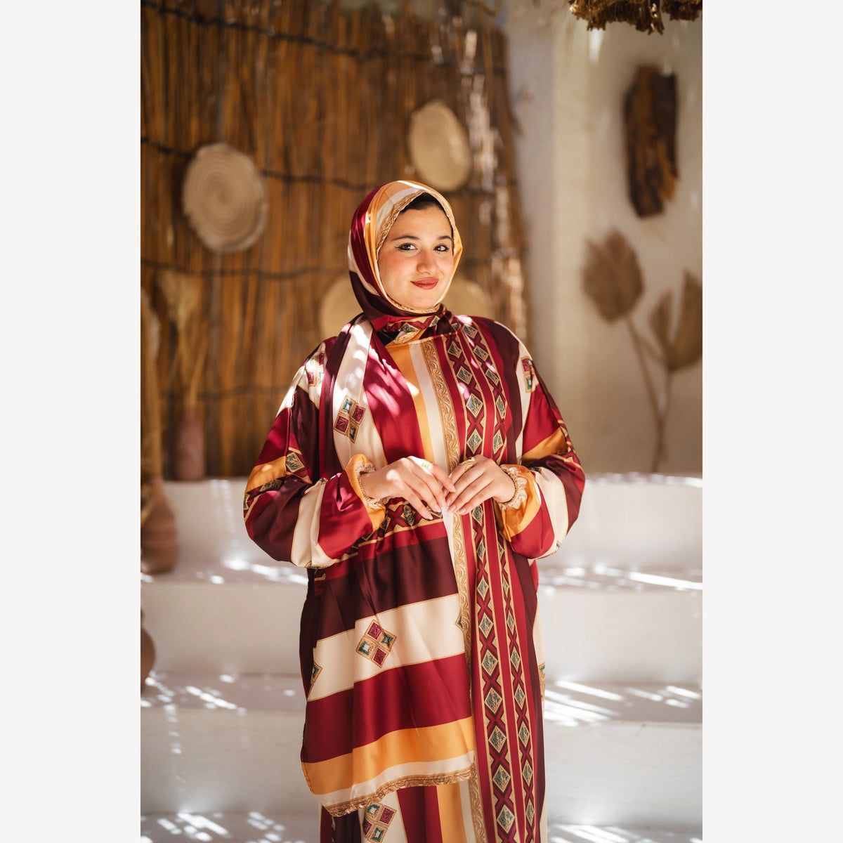 Tallah satin Isdal in burgundy mustard cream striped, closer three-quarter view with hands together.