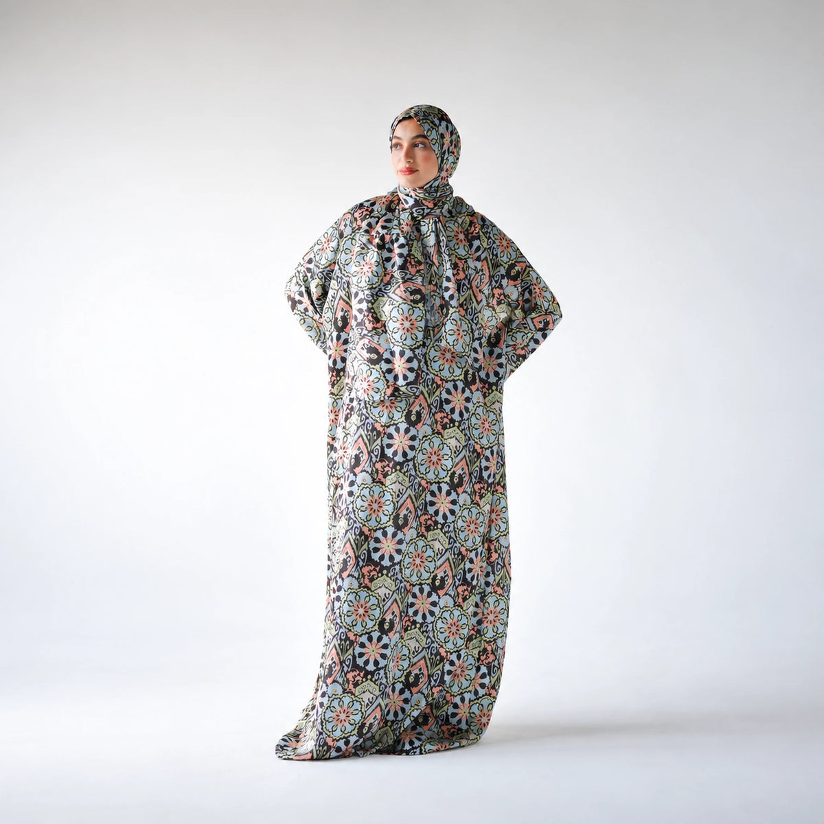 Multicolour satin Isdal with pastel blue, peach and green floral medallions on black, full-length view with hands at hips.
