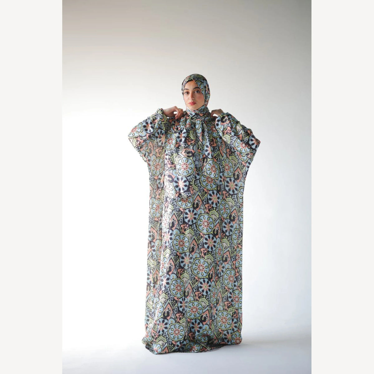 Tallah satin Isdal in navy green cream medallion, full-length front view with hands near head covering.