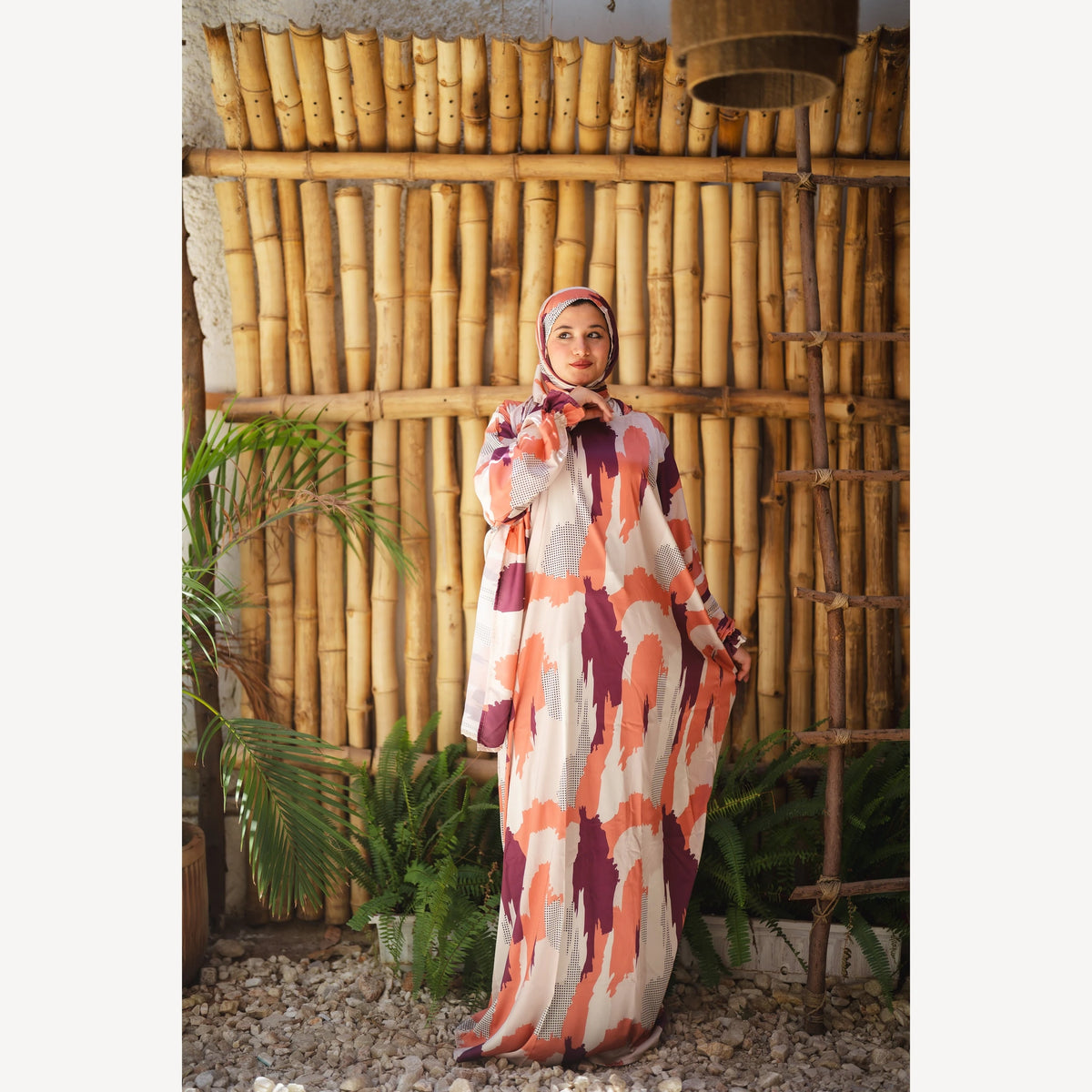 Tallah satin Isdal in orange plum cream brushstroke, full-length three-quarter view with hand near chin.
