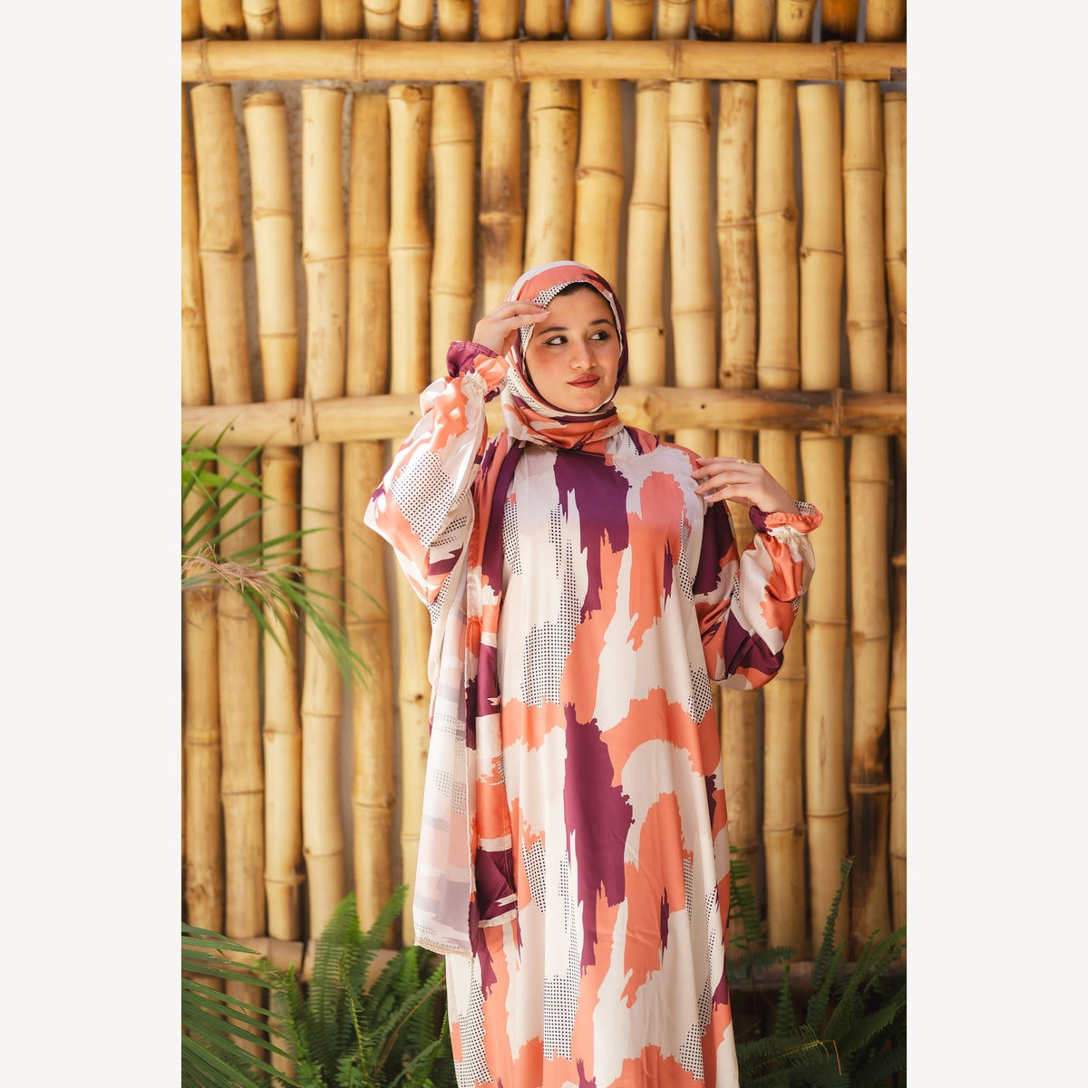 Tallah satin Isdal in orange plum cream brushstroke, closer front view with one hand near head covering.