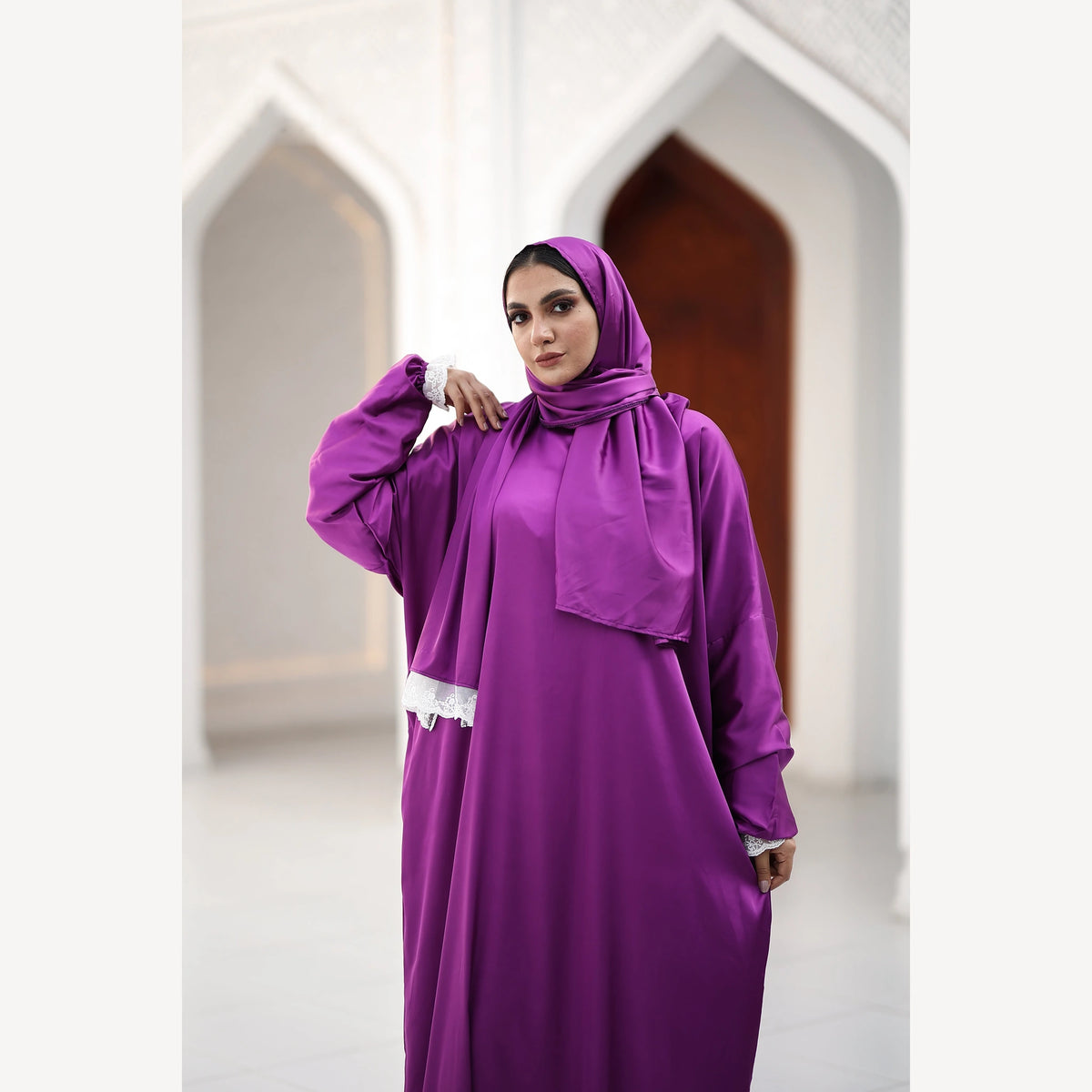 Purple satin Isdal with white lace cuffs and scarf trim, closer view with one hand raised near the shoulder.