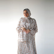 White and beige satin Isdal with brush-stroke stripes and daisy-like flowers, closer front view with hands at the waist.