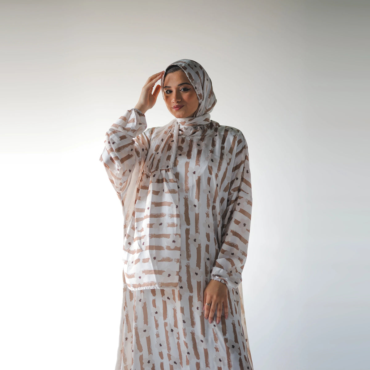 White and beige satin Isdal with brush-stroke stripes and daisy-like flowers, closer front view with one hand raised beside the head.